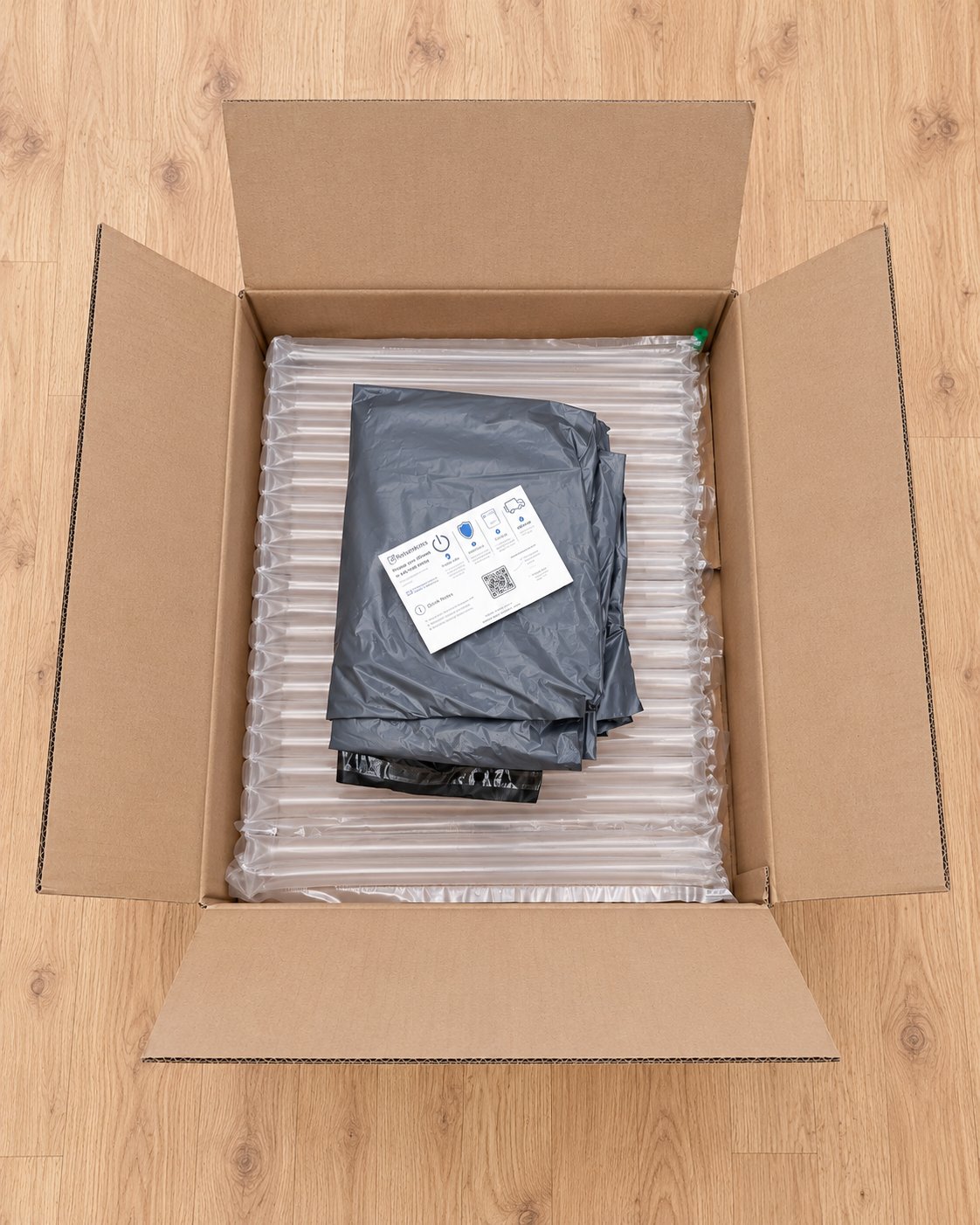 Monitor Return Kit: large open cardboard box lined with inflatable air-column padding, with grey mailing bags and a ReturnKits instruction card inside
