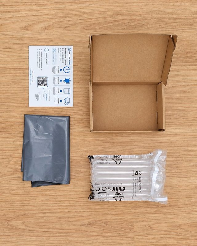Phone Return Kit laid out: small cardboard mailer box, inflatable air-cushion bag, grey mailing bag and ReturnKits instruction card