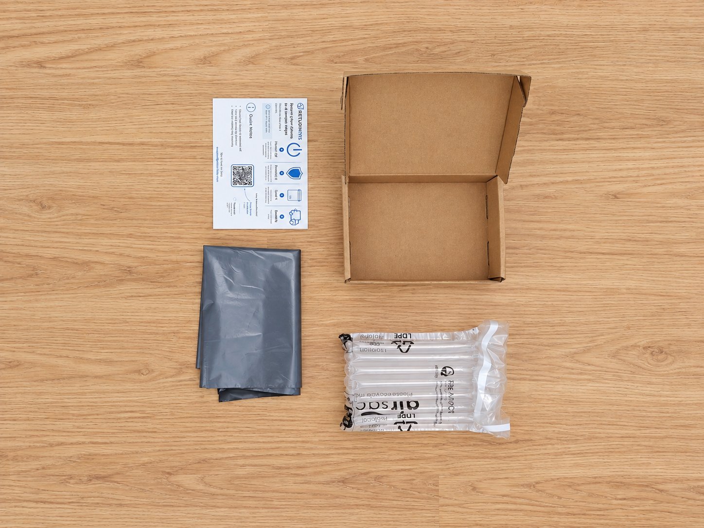Phone Return Kit laid out: small cardboard mailer box, inflatable air-cushion bag, grey mailing bag and ReturnKits instruction card